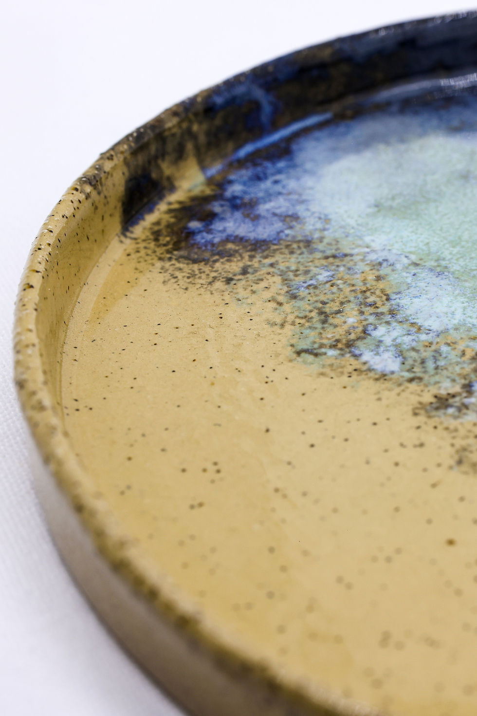 Close-up of a textured ceramic plate with tan and blue glaze