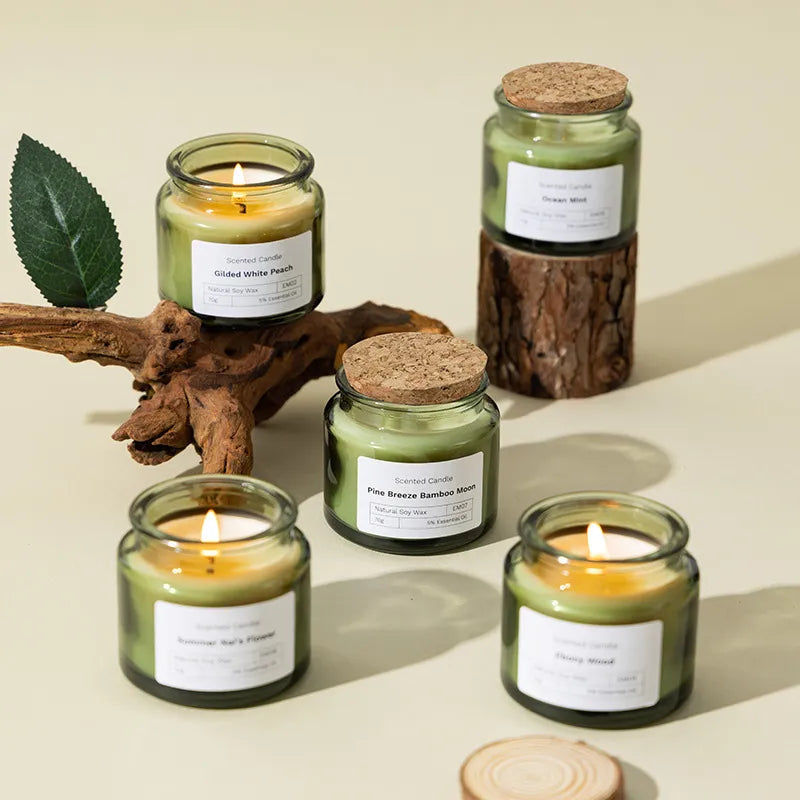 Five green jar candles, some lit, with wood and a leaf