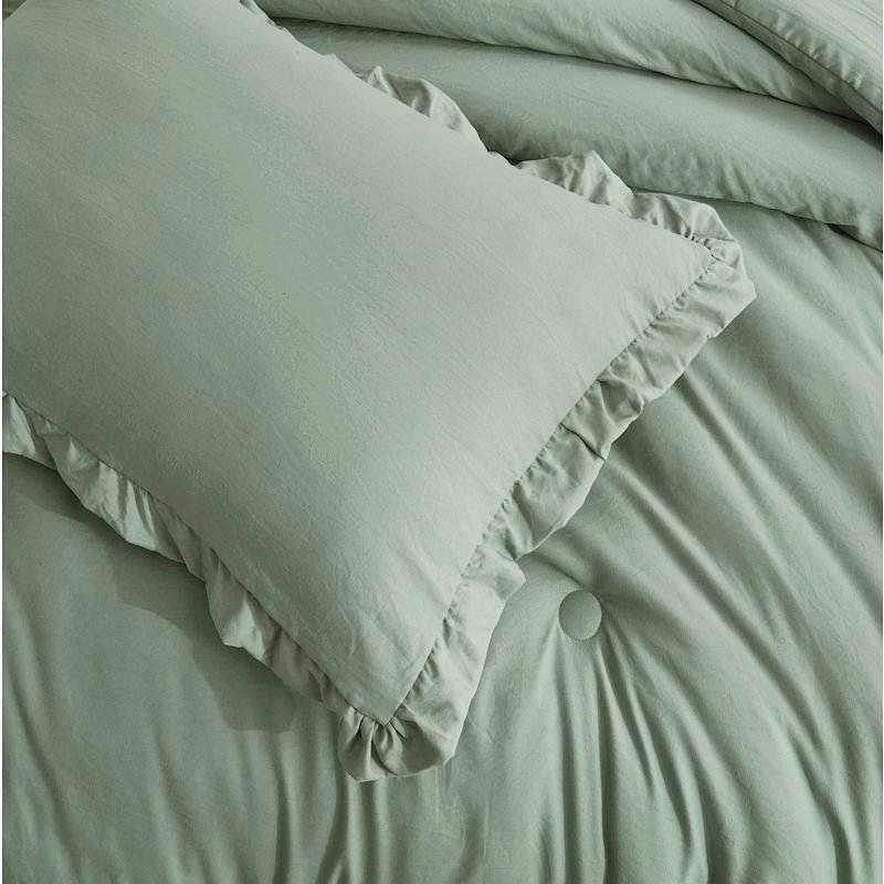 Sage green ruffled pillow on a matching tufted comforter