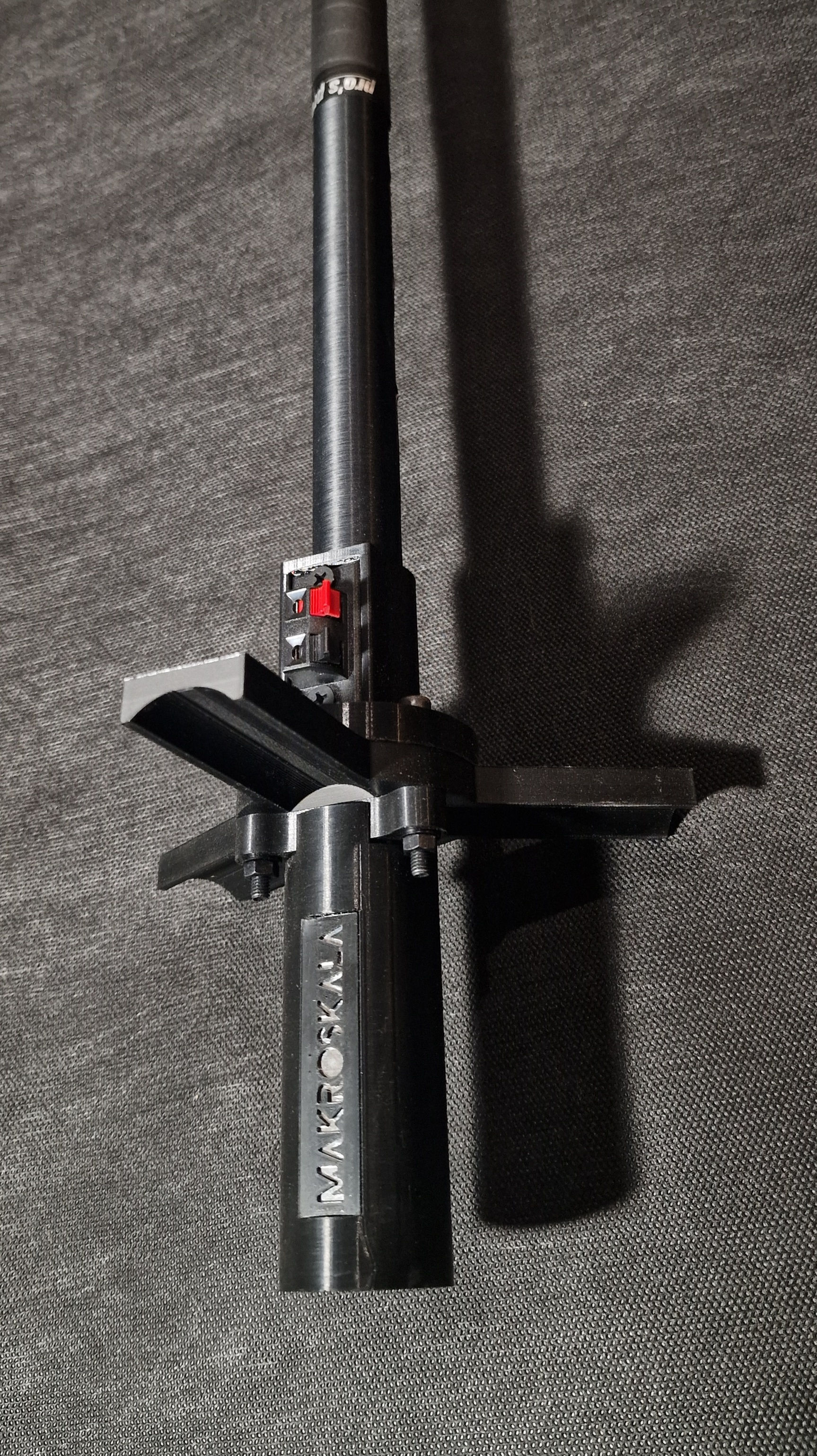 Część czarnego sprzętu z czerwoną opcją, na tle szarej powierzchni.