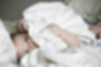 Newborn baby wrapped in a soft white blanket, wide awake and calm - promoting safe and peaceful infant sleep