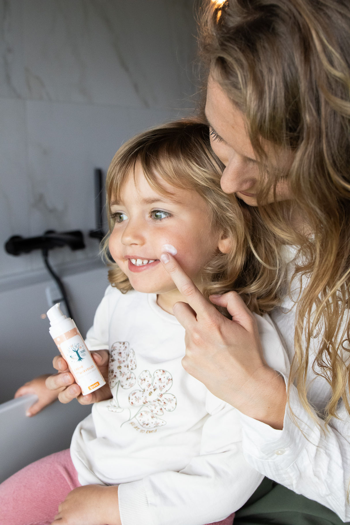 Crème de visage naturelle pour enfant disposée sur un visage souriant