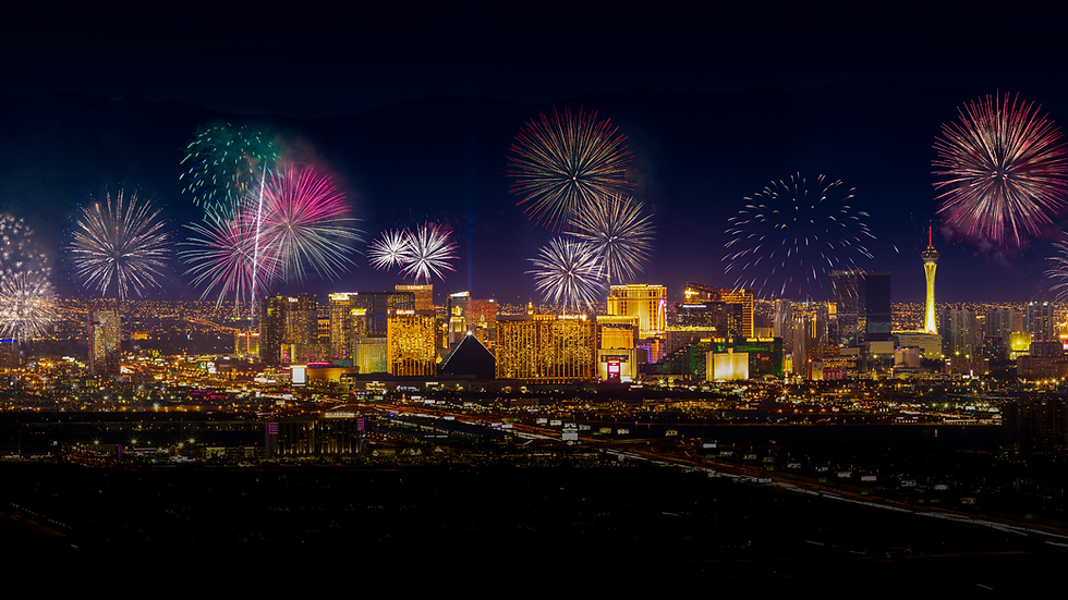 Fireworks explode in vibrant colors over a brightly lit city skyline at night, creating a festive and celebratory atmosphere.