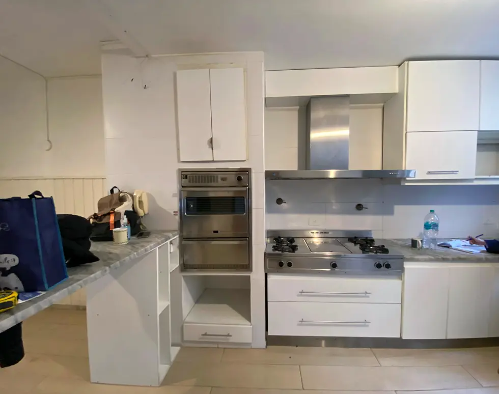 Existing white kitchen before renovation in a Buenos Aires apartment.