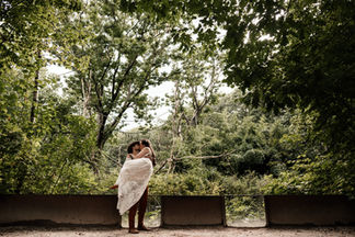 Bruidegom tilt zijn kersverse vrouw de lucht in tijdens de fotoshoot in het groene bos van De Apenheul in Apeldoorn