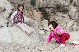 Twee meisjes van 1,5 en 5 jaar spelen op het kiezelstrand aan de Costa Brava van Spanje.