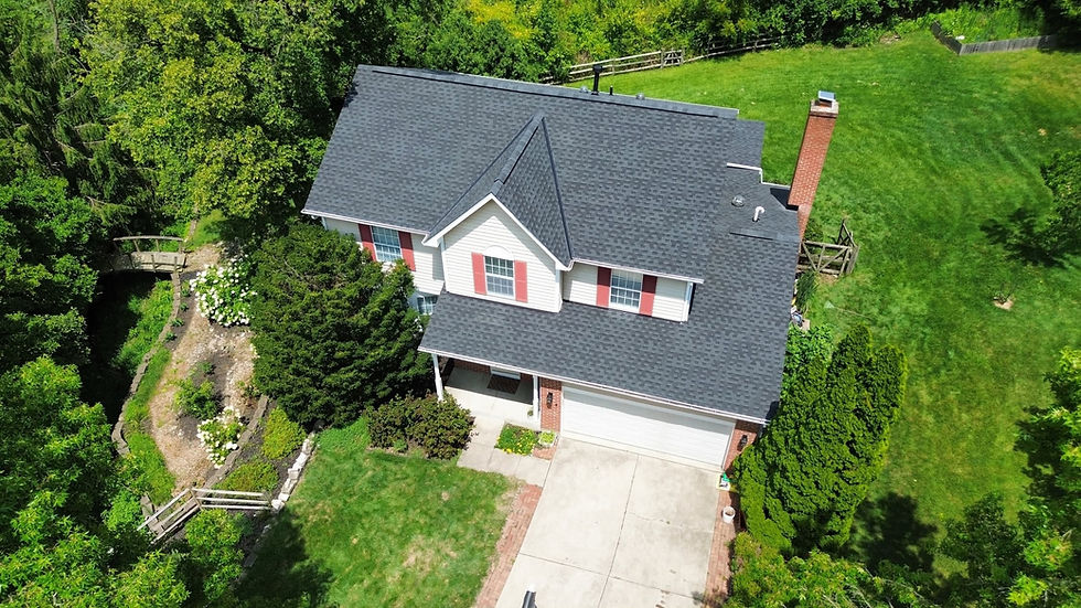 Aerial view of a gray shingle roof on a two-story home with red shutters and a brick chimney