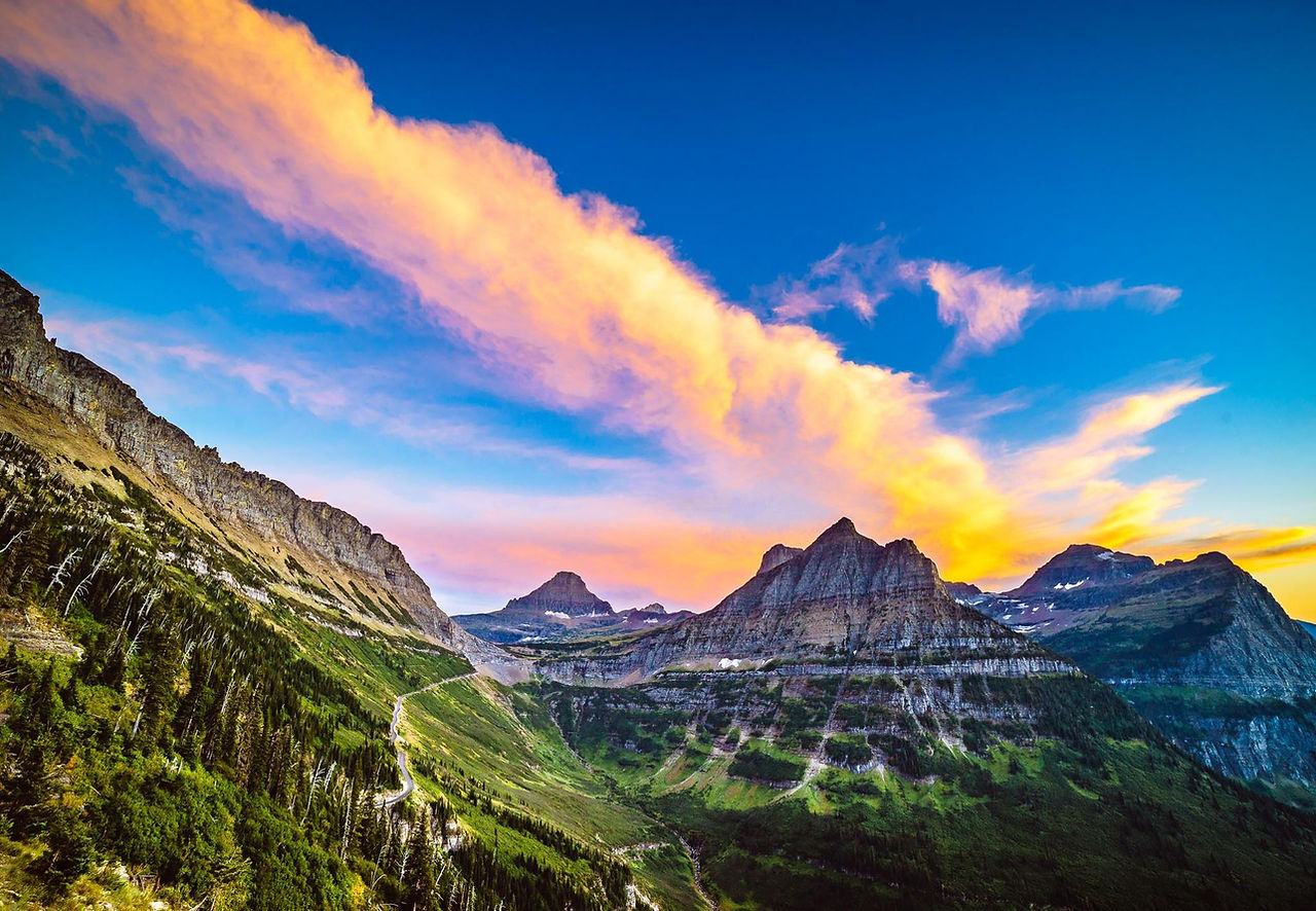 Colorful clouds over rugged green mountains
