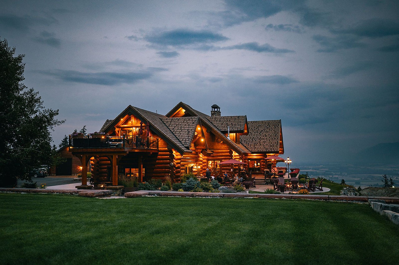 The lodge at blue hour with lit windows and a green lawn