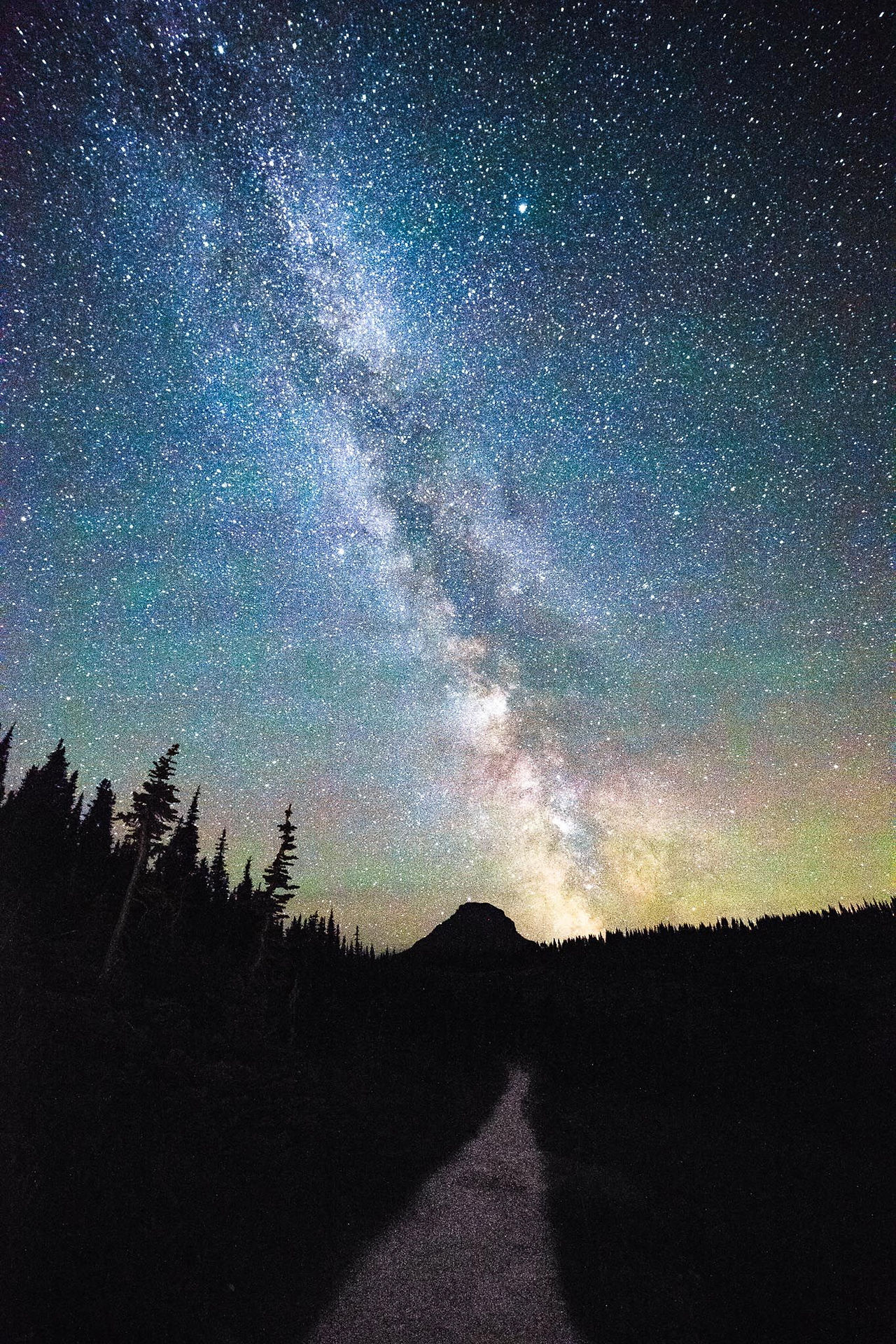 The Milky Way over a dark forested ridge
