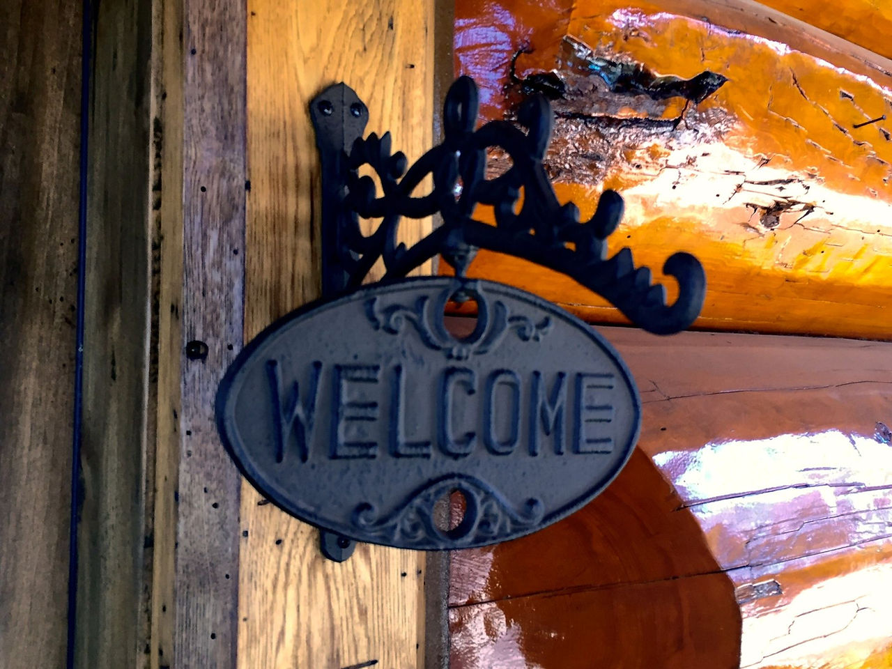 A cast-iron welcome sign on a log wall