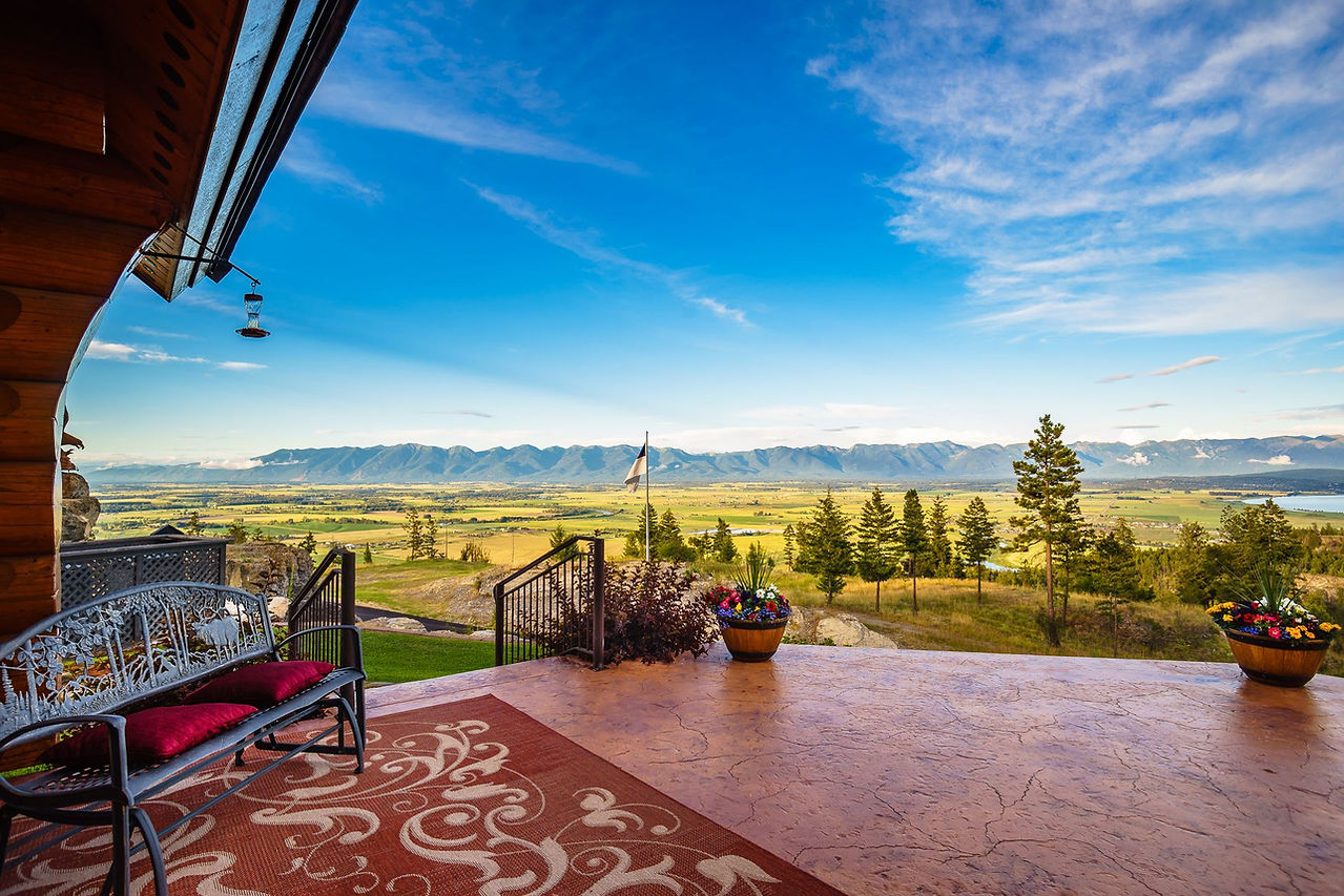 Patio benches overlooking the sunlit valley and distant mountains