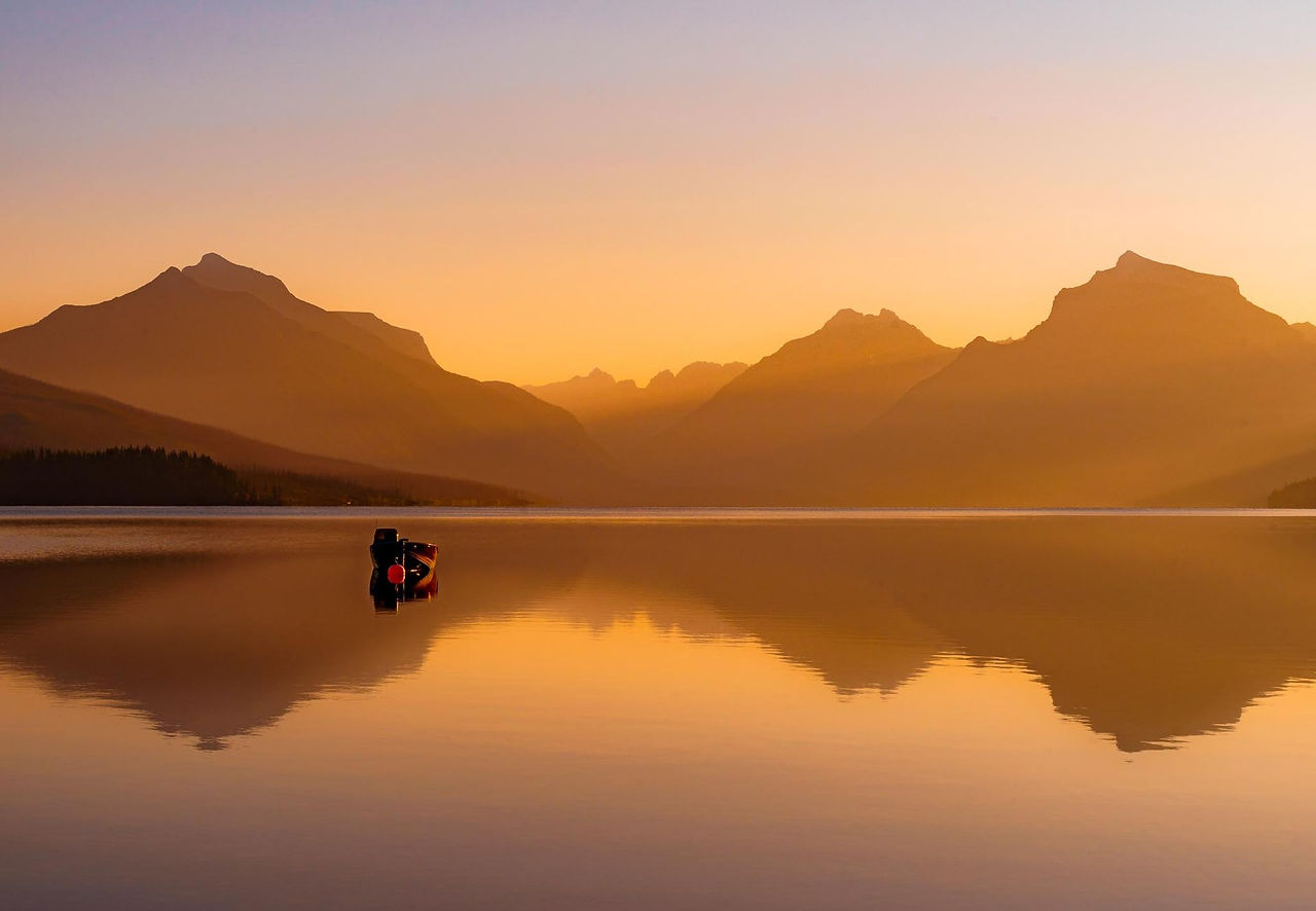 A canoe on a calm lake at sunrise