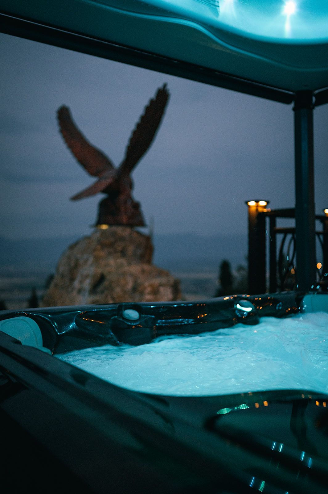 A private hot tub at dusk beside an eagle sculpture