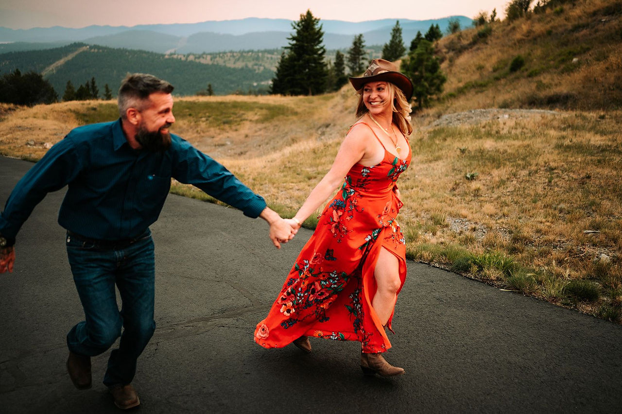 A couple running hand in hand down a mountain road