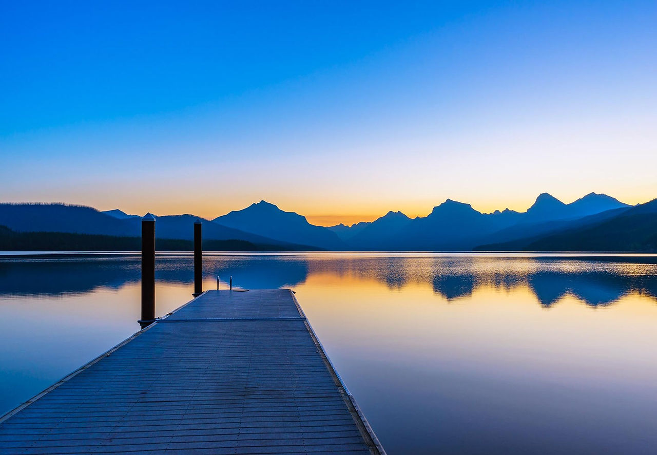 Wooden dock on a glassy mountain lake at sunrise