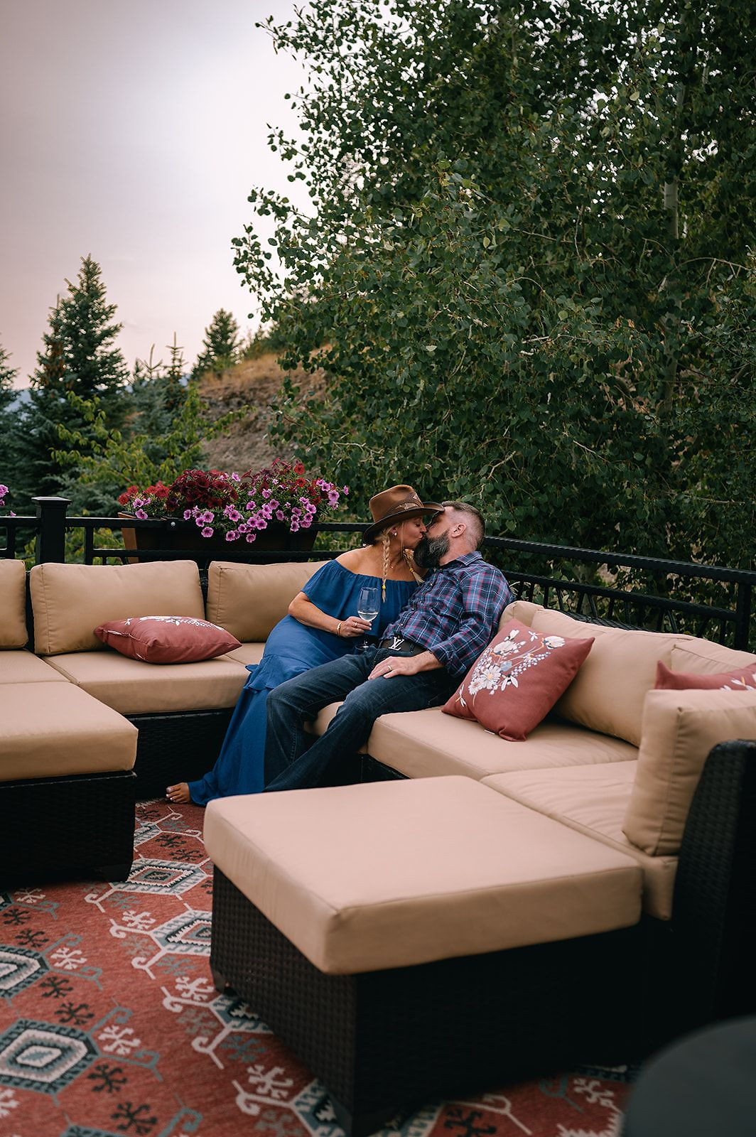 A couple relaxing on a cushioned patio sofa among flowers