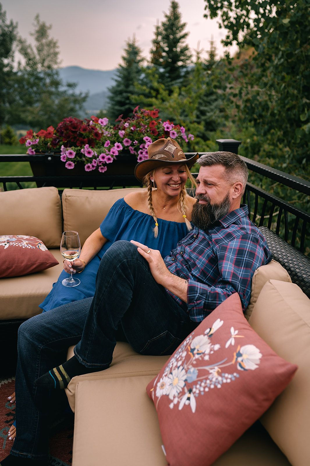 A couple on an outdoor sofa with a mountain view at sunset
