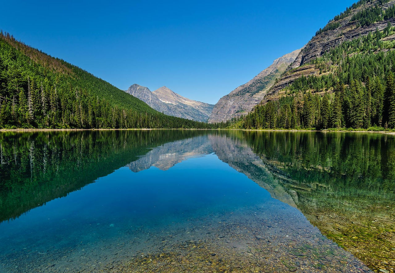Mountain lake reflecting pine-covered slopes