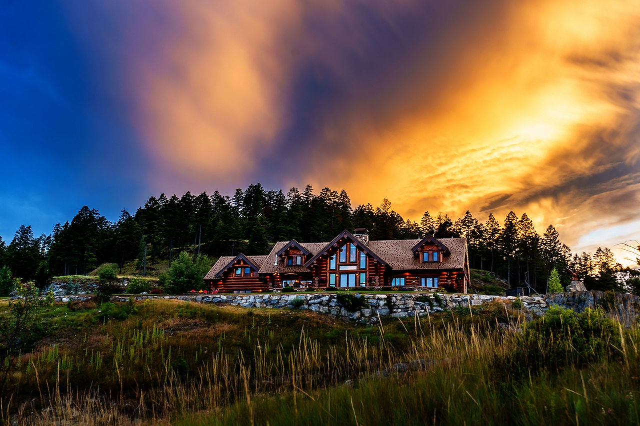 Coyote Bluff Estate log lodge beneath a blazing orange Montana sunset