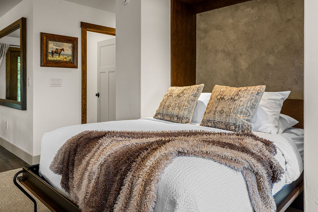Somers House: the queen Murphy bed made up with patterned pillows and a fur throw