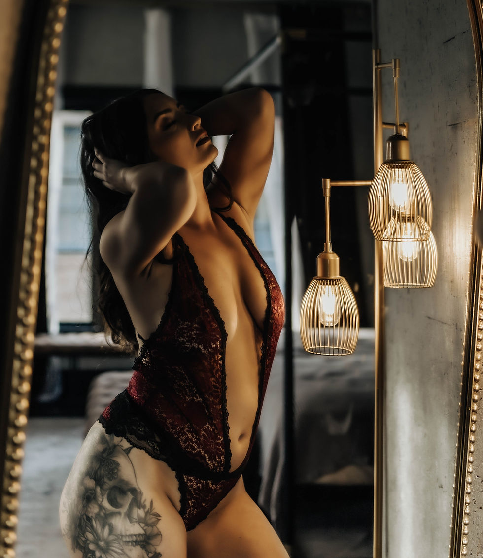 A classic, body-positive boudoir portrait featuring elegant moody lighting in lace bodysuit.