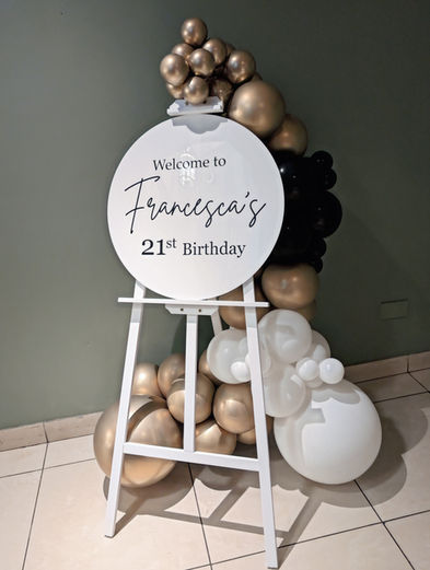 Custom white easel welcome sign for a 21st Birthday event, decorated with white and gold balloons.
