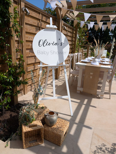 A beautiful circular 'Welcome to Olivia's Baby Shower' sign displayed on a white easel
