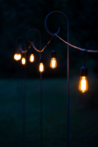 A close-up of a decorative garden lamp with warm, glowing Edison-style light bulbs against a dark background at night.
