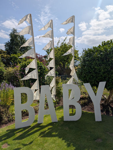 Giant white freestanding 'BABY' letters for hire, a perfect statement prop for an outdoor baby shower, gender reveal, or christening garden party.