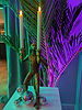Gold monkey candle holder among palm leaves, lit in green and purple, from our Neon Tropics theme