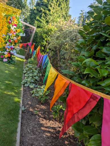 A path winding through a lush garden with colourful triangular bunting strung between the greenery.