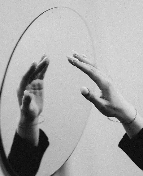 Photo of hand hovering over oval mirror to symbolize body image