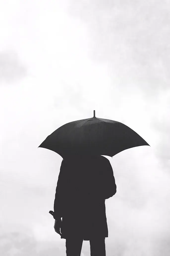 Photo of person holding an umbrella on a cloudy day, symbolizing anxiety