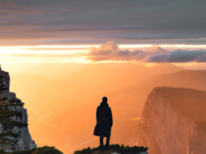 Visionary leadership concept showing a person overlooking a landscape at sunset, representing future thinking, uncertainty, and investment beyond metrics