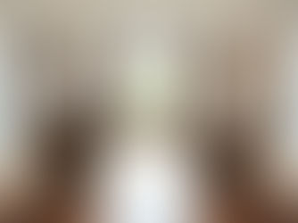 Two brown armchairs face each other in a spacious room with wood flooring. A large window with beige curtains lets in natural light. Calm ambiance.