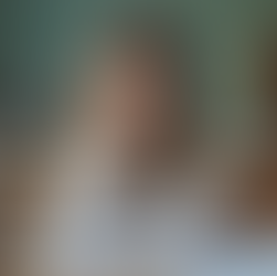 Eye-level view of a young girl sitting at a desk with scattered school books and a thoughtful expression