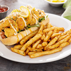 fried pork chops served on a black plate with roast potatoes