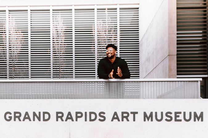 Grand Rapids Art Museum Membership Director Michael Catching stands at the museum's front steps. He is smiling and looking off to the left of the image.