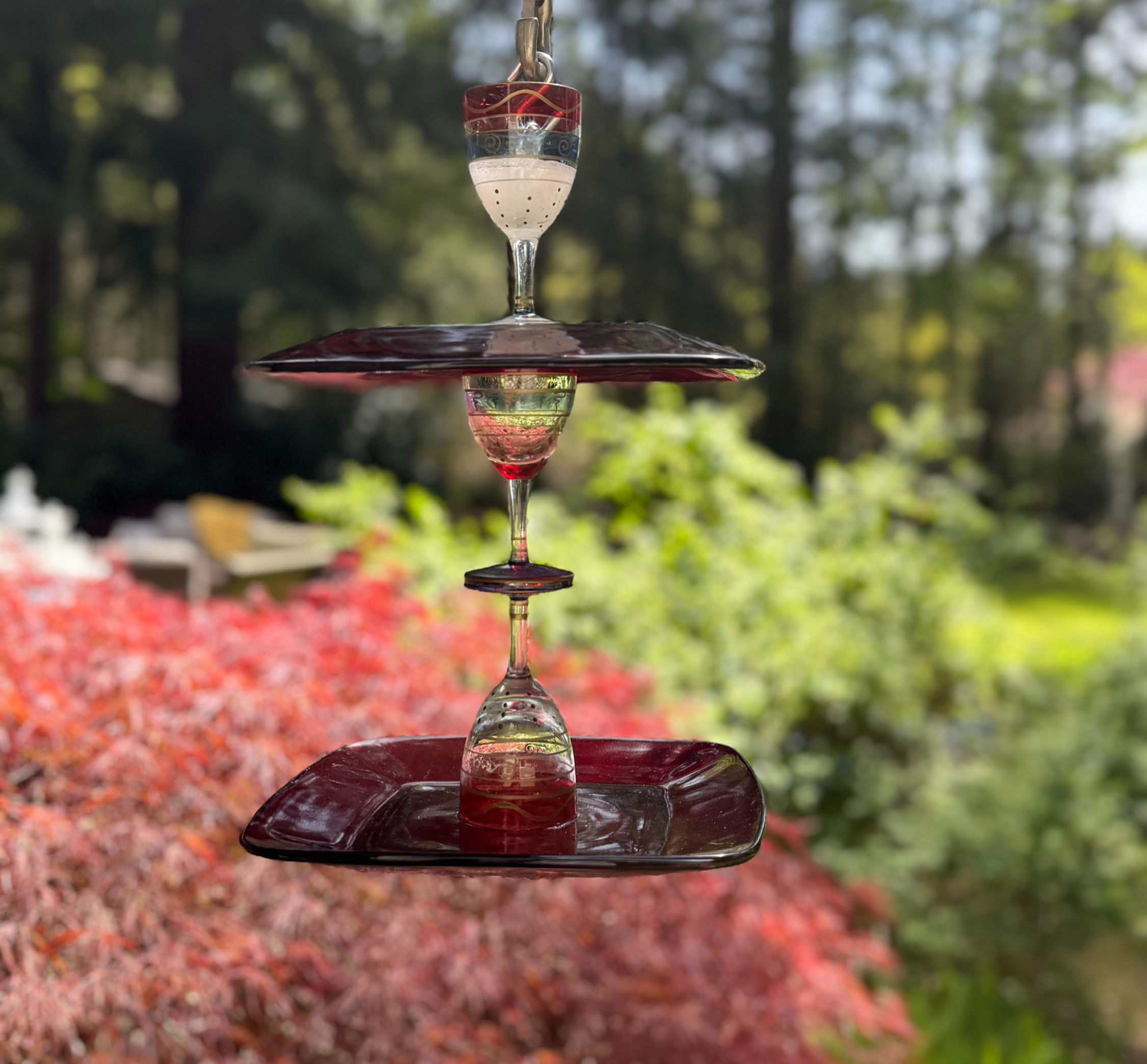 Tiered ruby glass bird feeder in a garden