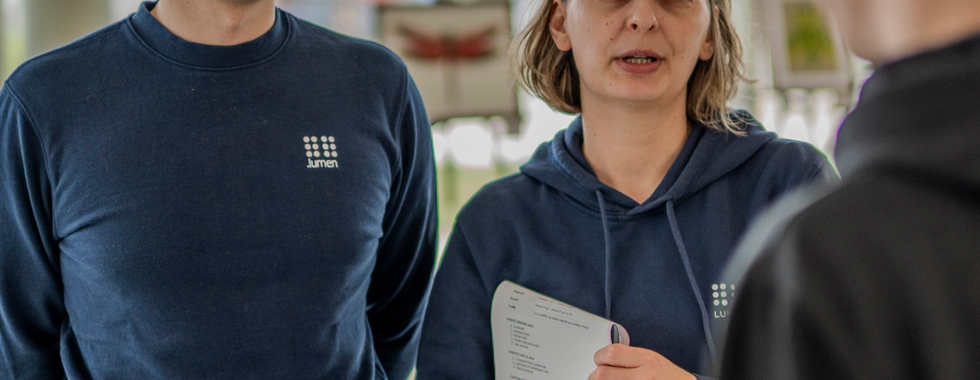 14. Doi membri ai echipei .lumen asciltă un participant care poartă ochelarii în timpul unei sesiuni indoor.