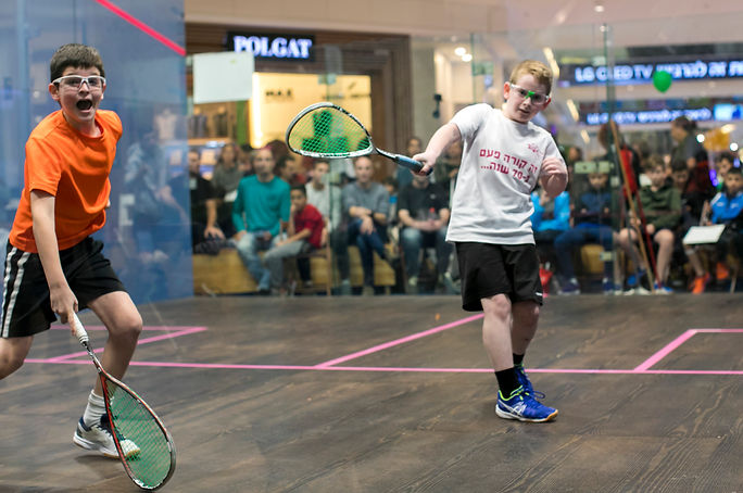 Boy with an orange t shirt playing squash