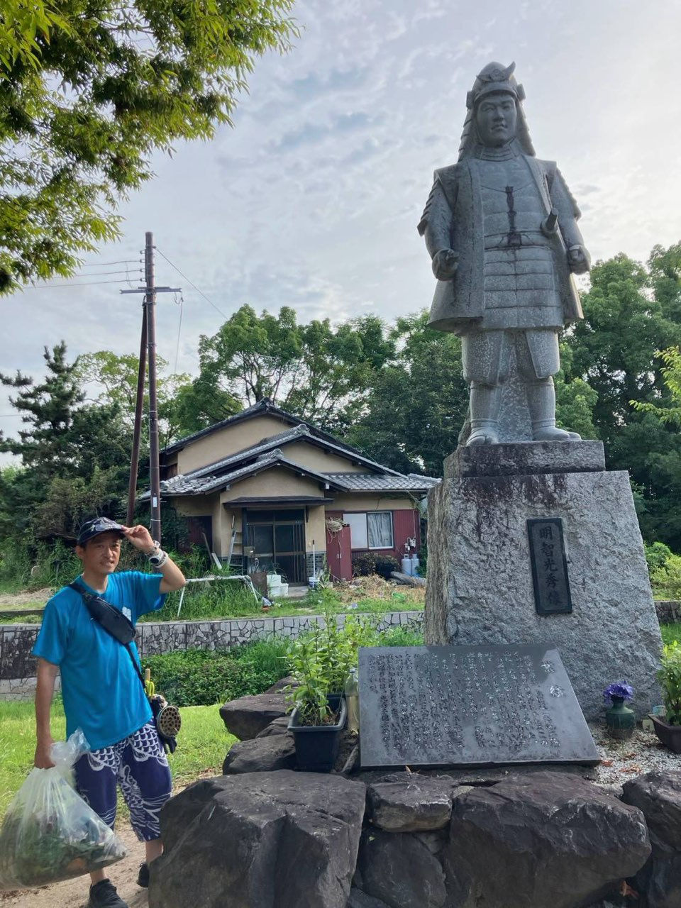 坂本城址公園で、桔梗の剪定などのお世話を担当されている吉本さん(明智光秀公の石像の前にて)。