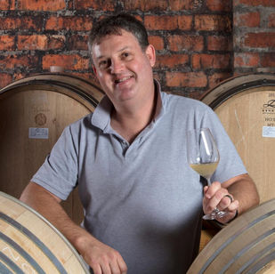 man holding a wine glass in a winery cellar