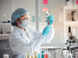 Scientist with microscope and holding test tube