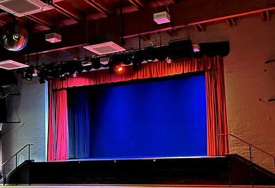 Thetford Carnegie stage with blue curtains drawn and red events lighting