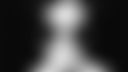 Person wearing black goggles in a close-up, monochrome image. The background is dark, and the mood is mysterious and intense.