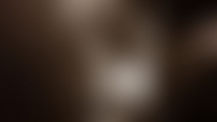 Guitarist in sunglasses playing energetically on stage under dramatic spotlights, exuding joy. Sepia tone adds vintage feel.