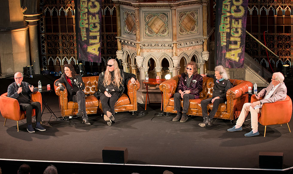 Five people sit on stage in a panel discussion, with "The Reverend Alice Cooper" banner behind them. Ornate backdrop and casual setting.