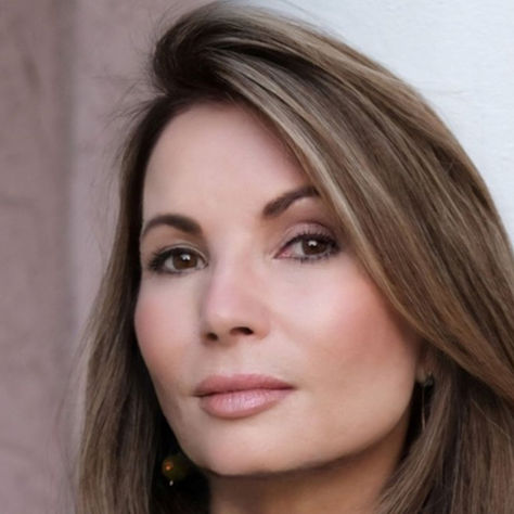 Woman with brown hair looks forward against a soft pink and white background. The mood is calm and contemplative. No text visible.